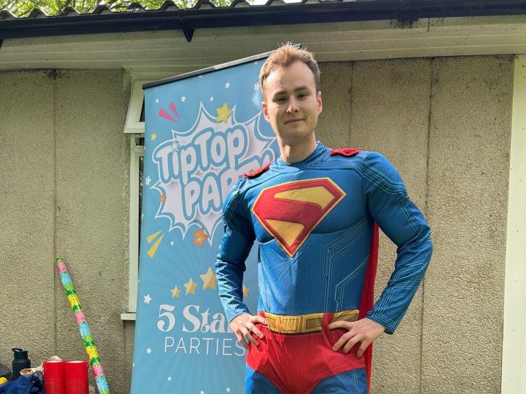Superhero party entertainment with games, activities, and laughs. A person dressed as Wonder Woman holding a bundle of coloured balloons.