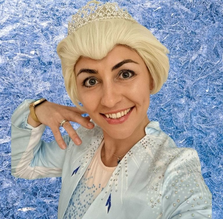 Kids' party with Elsa Young girl dressed as Elsa from Frozen, smiling against a snowy background.